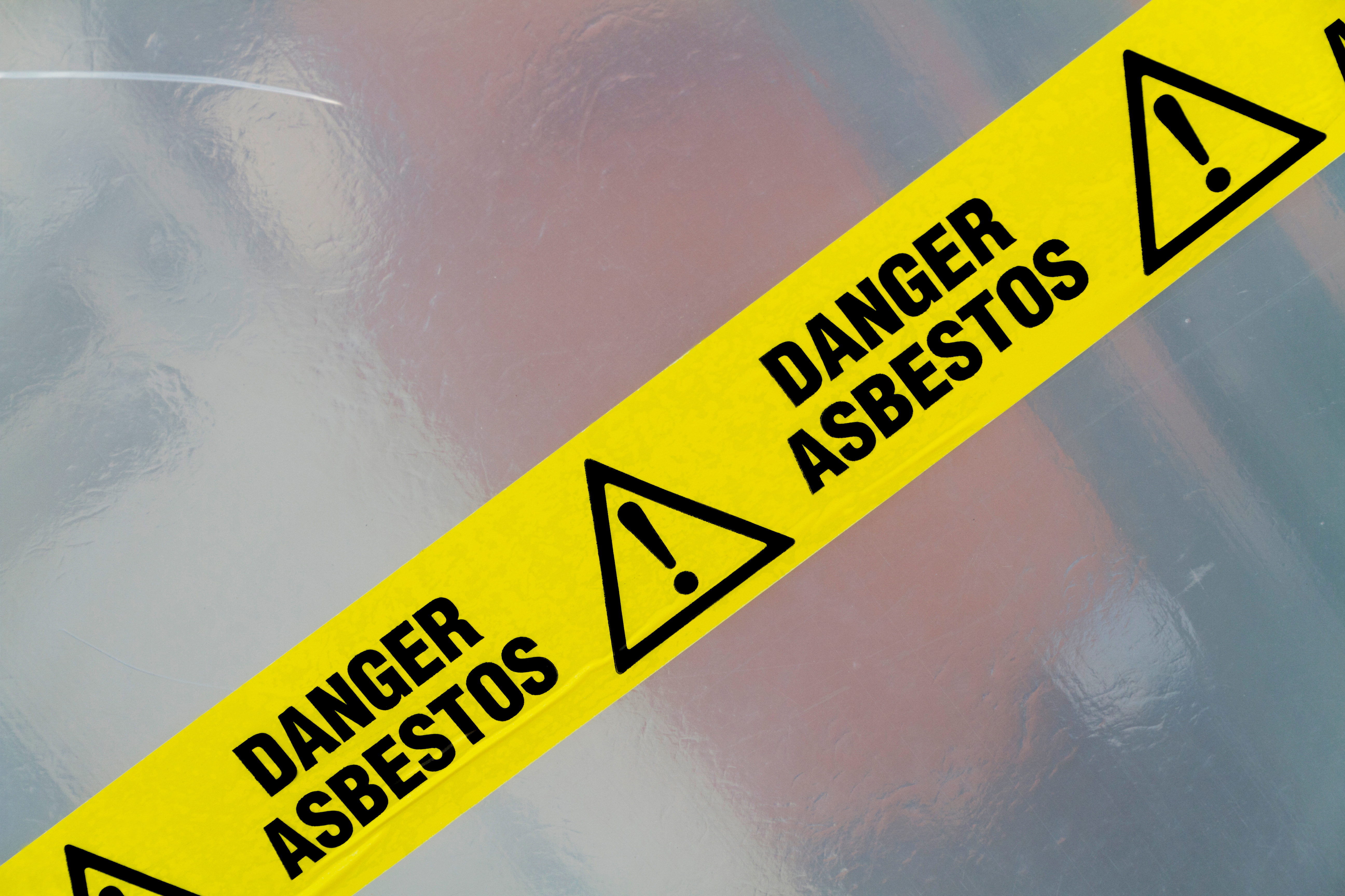 An image of yellow caution tape that says danger asbestos on it.